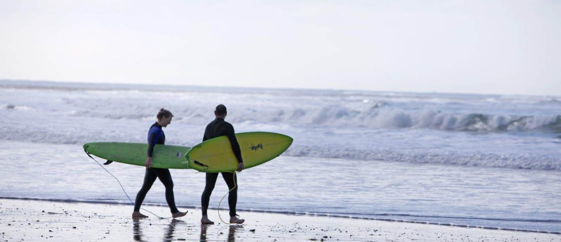 two high school students surfing at the beach